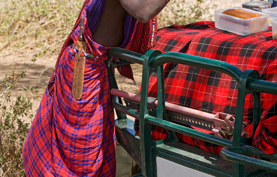 Young masai warrior preparing a picknic on the hood of the car.See also my LB: