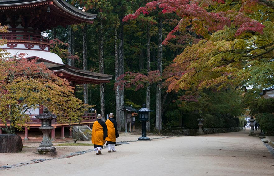 Buddhist monks walking past temple in Koyasan, Mt Koya, Japan during autumn. 