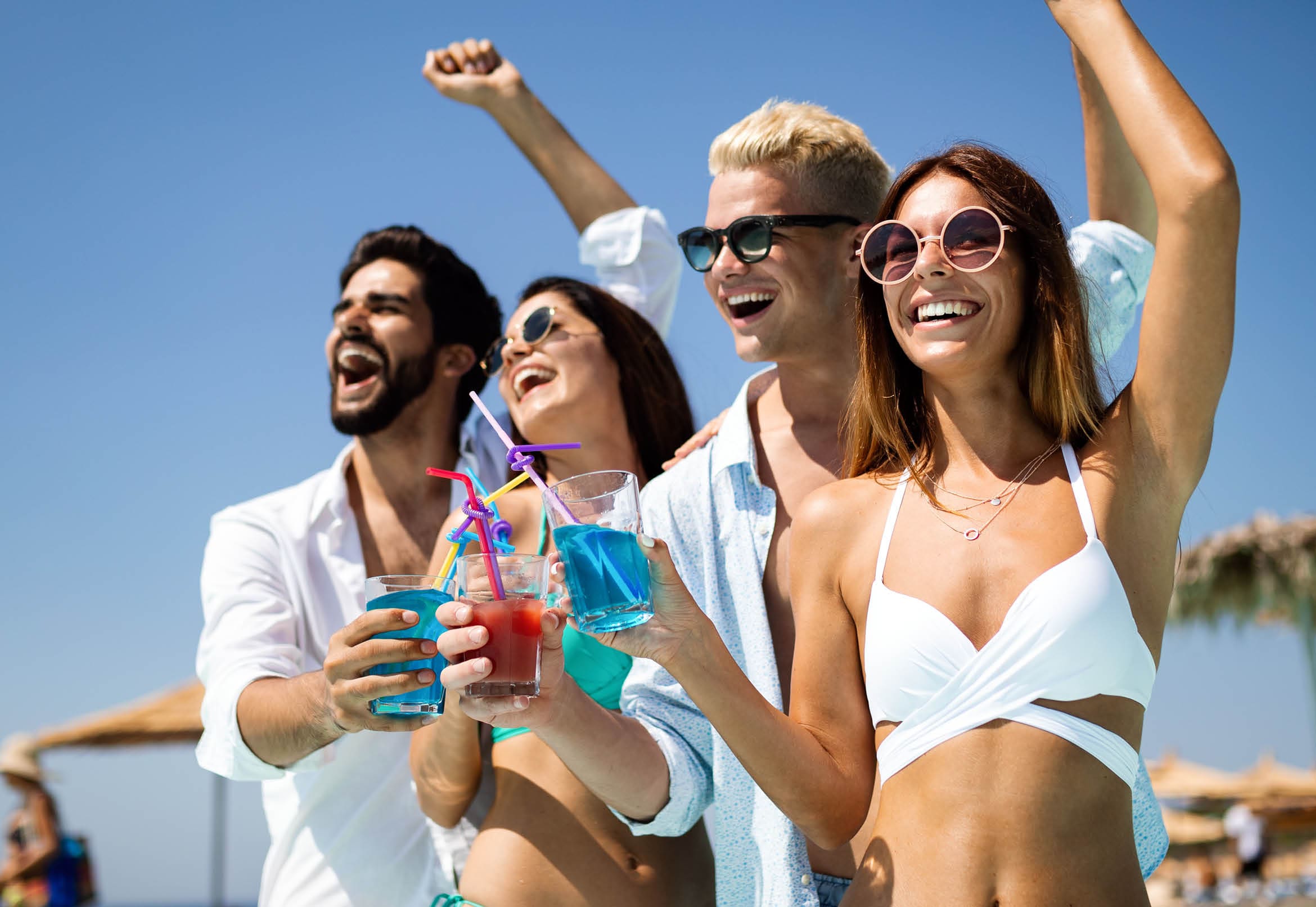 Group of happy friends having fun dancing at swimming pool with cocktails