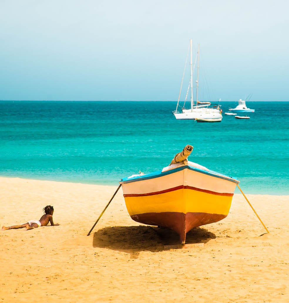 Cabo Verde No Stress. Sunny tropical Sal island vacation background of African child silhouette enjoying sandy Santa Maria beach with colourful boats and turquoise water seascape on Cape verde islands