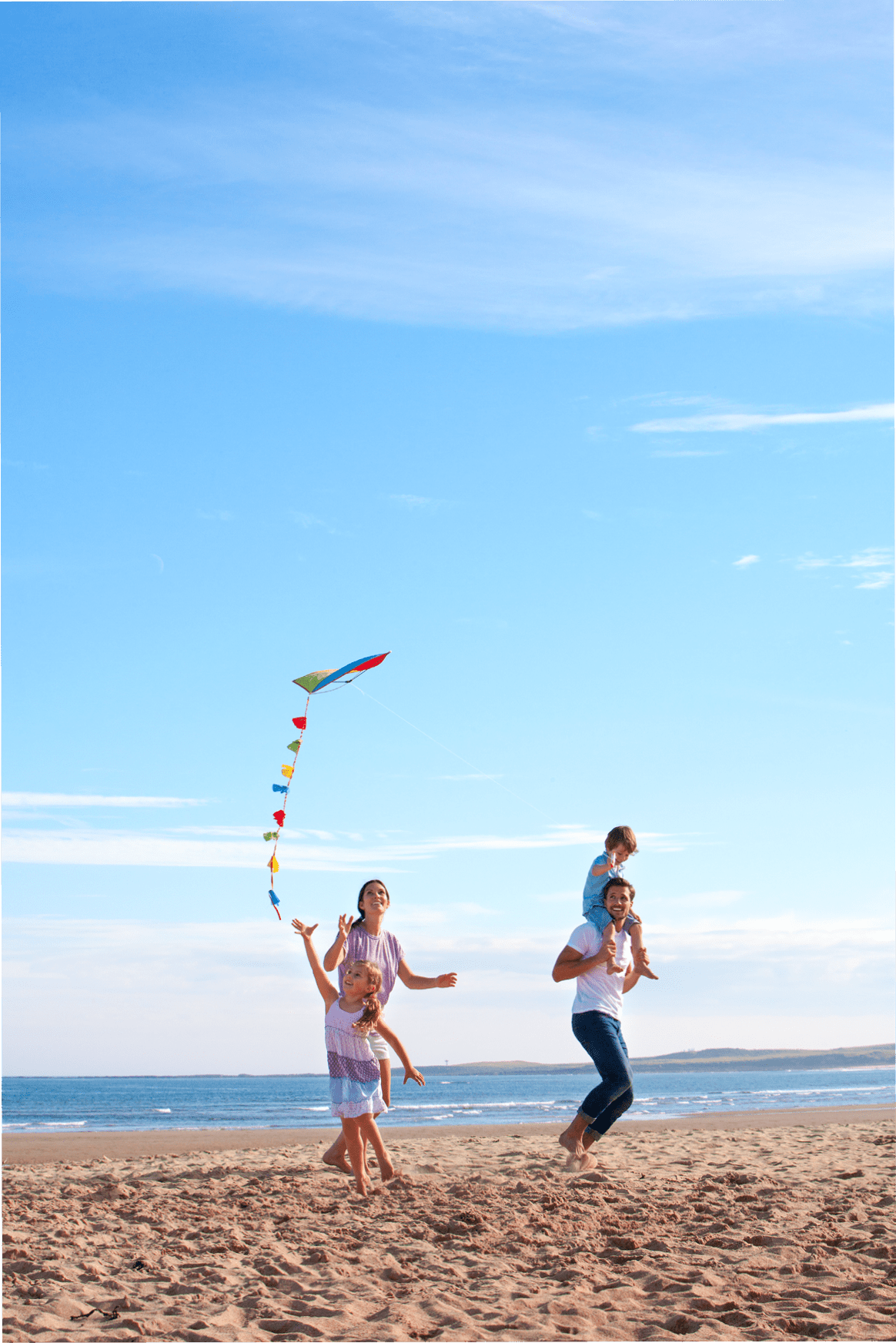 Family of four flying a kite together on the beach