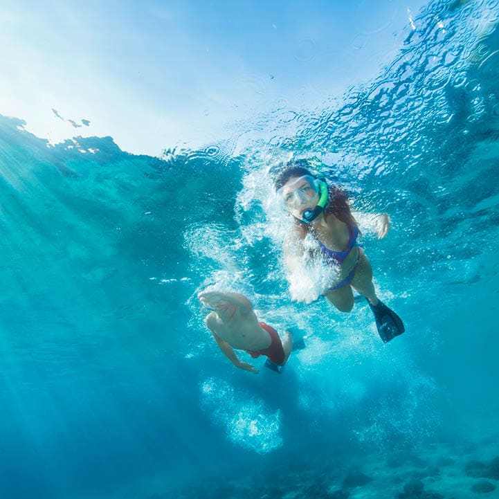 Snorkeling adventure. Best friends. Young man and woman, diving into the sea. Underwater turquoise lagoon. Happy teenage couple swimming, joy into the crystal clear sea. Mediterranean beach. Summer sea romance.