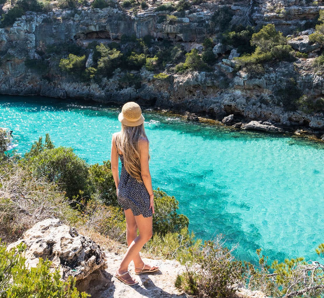 Rear view of woman with long blonde hair in cala pi, Mallorca, balearic islands. Turquoise water rounded by rocks