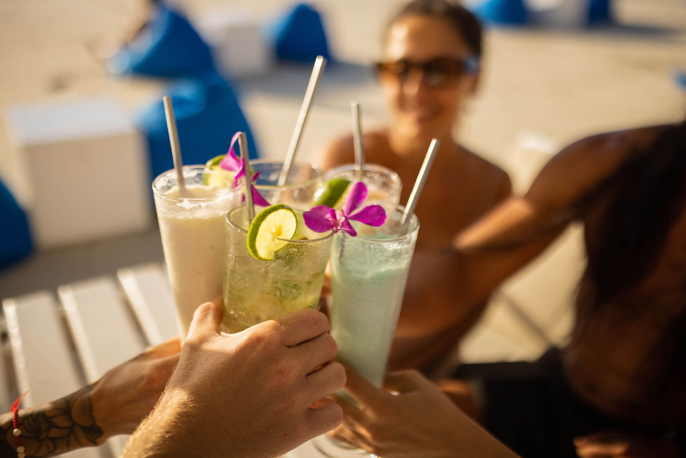 Multiracial friends drinking coctails at the beach bar, and having good time during their vacation