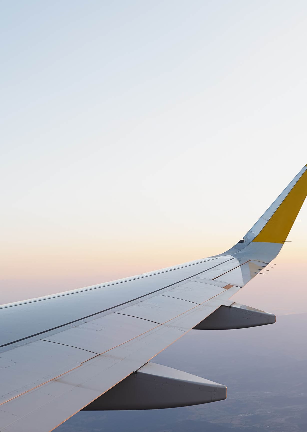 Wing of modern aircraft flying in cloudy blue sky during trip
