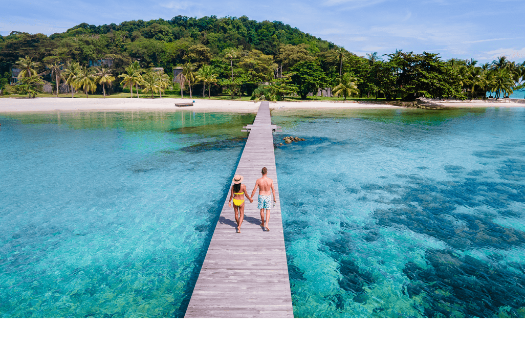 couple walking at a wooden pier in the ocean of Koh Kham Trat Thailand a tropical island near Koh Mak Thailand. white sandy beach with palm trees