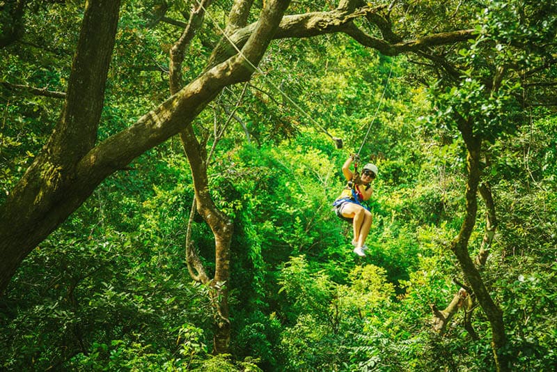 woman in her 40s doing a Canopy Tour Costa Rica, zip lines between trees.