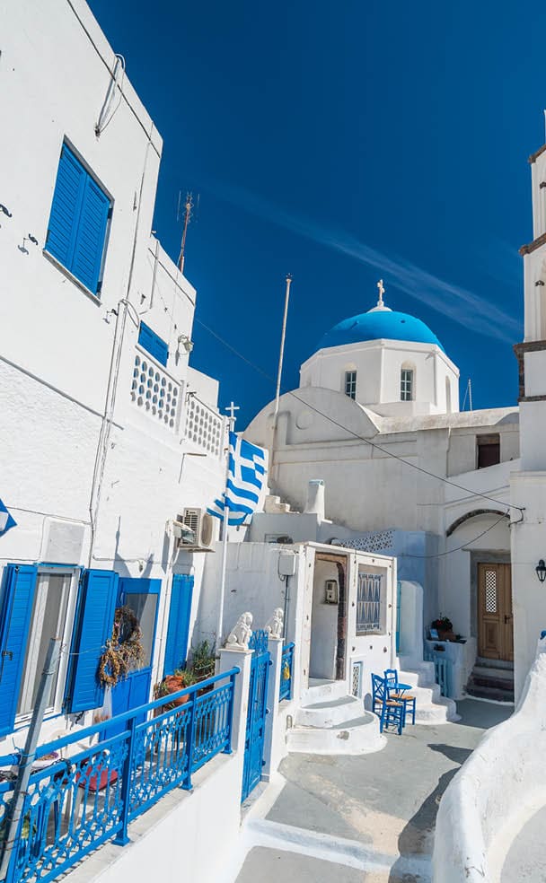 typical greek church and flag in the ancient town of pyrgos on santorini island greece