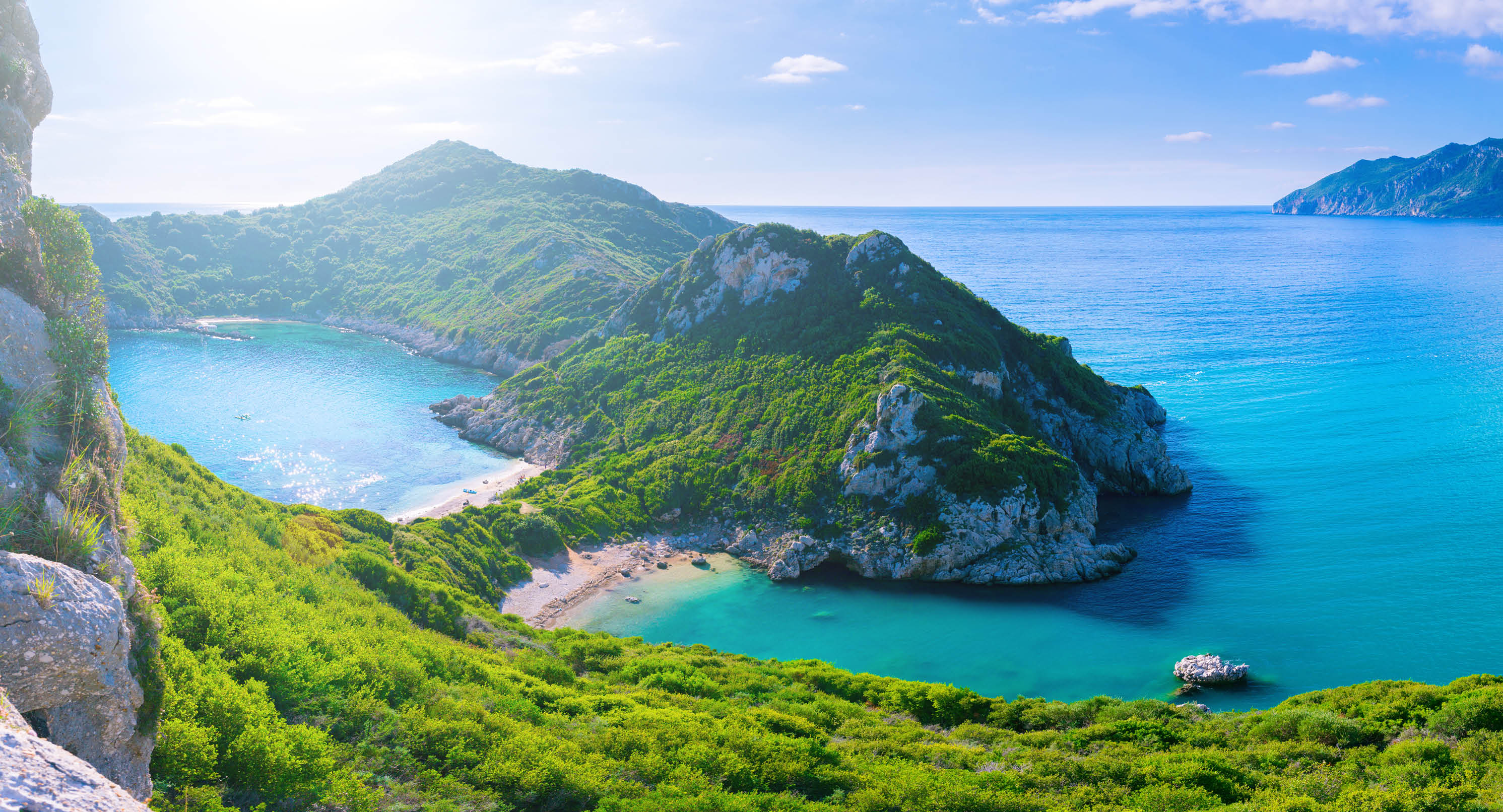 Beautiful summertime panoramic seascape. View of the cliff into the crystal clear azure sea bay and distant islands. Unique secluded beach. Agios Stefanos cape. Afionas. Corfu. Greece.
