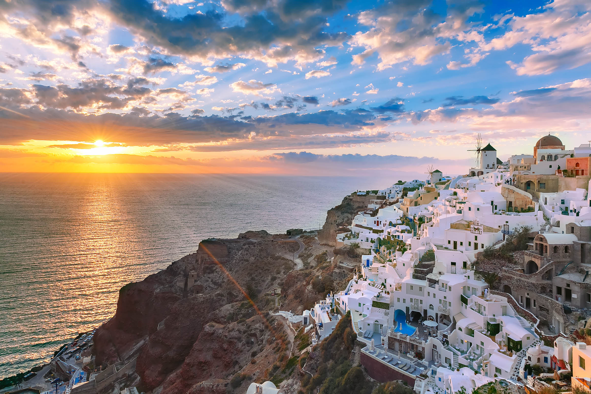 Picturesque view, Old Town of Oia or Ia on the island Santorini, white houses, windmills and church with blue domes at sunset, Greece
