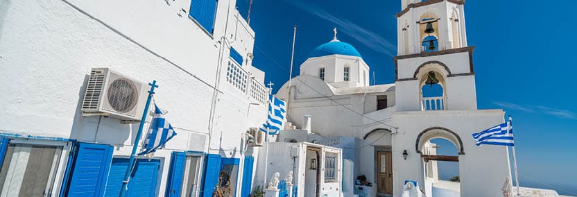 typical greek church and flag in the ancient town of pyrgos on santorini island greece