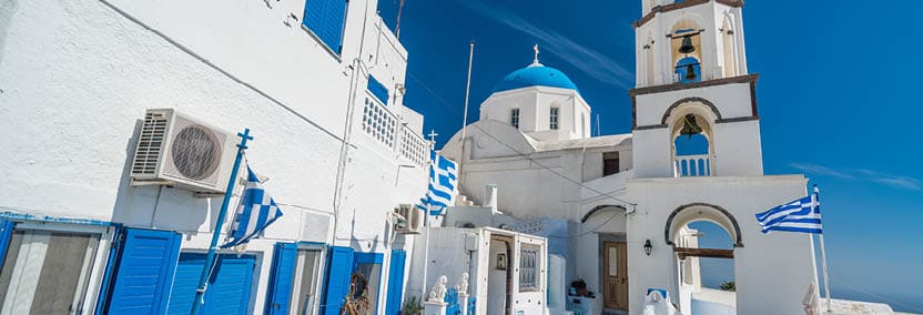 typical greek church and flag in the ancient town of pyrgos on santorini island greece