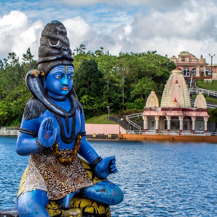 Blue Shiva statue on the background of the Indian temple and tropical greenery