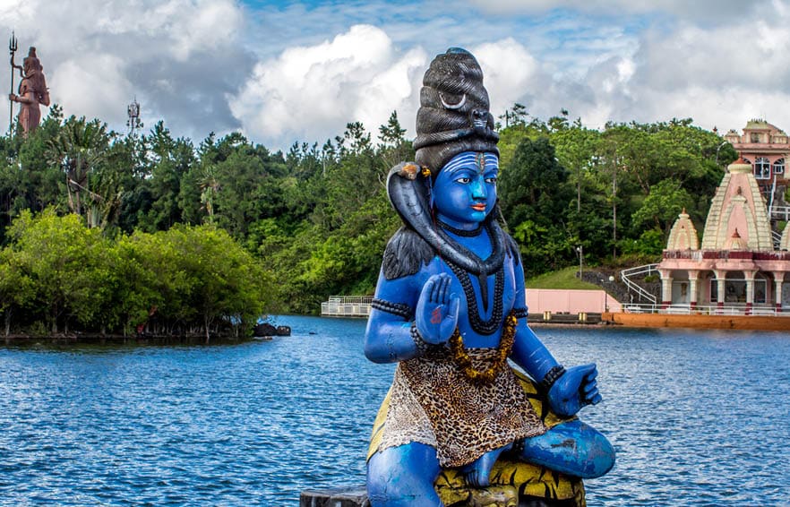 Blue Shiva statue on the background of the Indian temple and tropical greenery