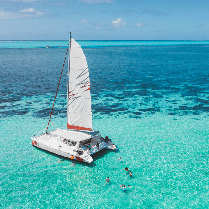 Family and friends swimming near a beautiful catamaran in the paradise turquoise lagoon of the east coast of Mauritius