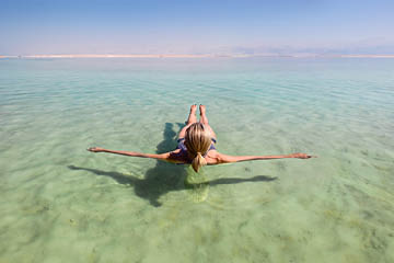 Blonde woman floating in the turquoise waters of the Dead Sea