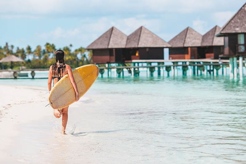 Beautiful surfer woman ready to surfing in turquoise sea, on stand up paddle board at exotic vacation