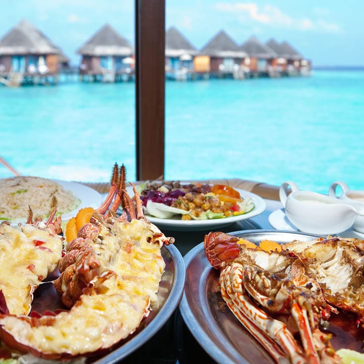 Two plates with lobster on table at window with view on ocean