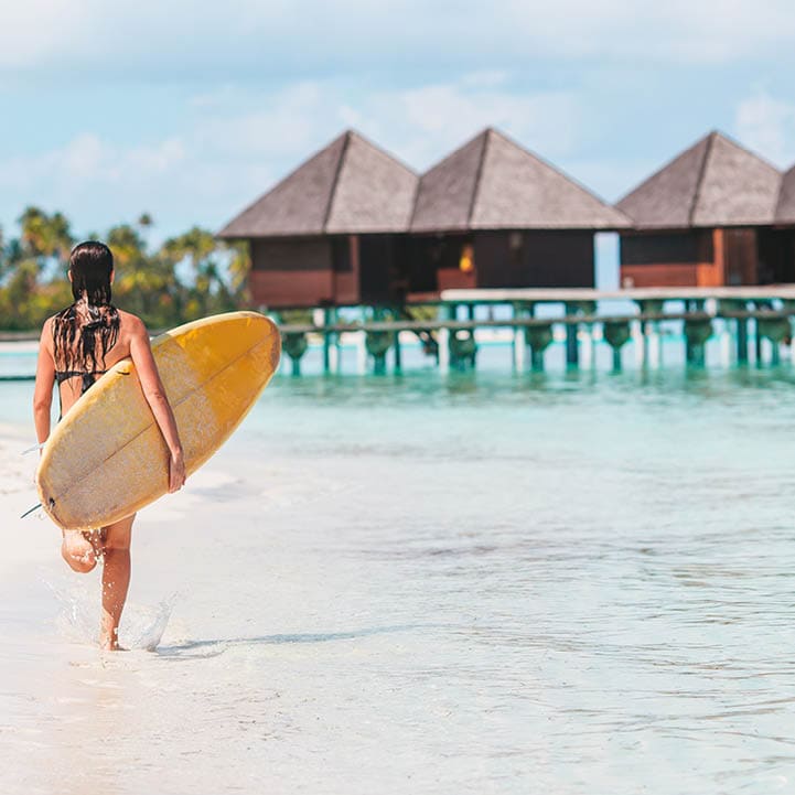 Beautiful surfer woman ready to surfing in turquoise sea, on stand up paddle board at exotic vacation