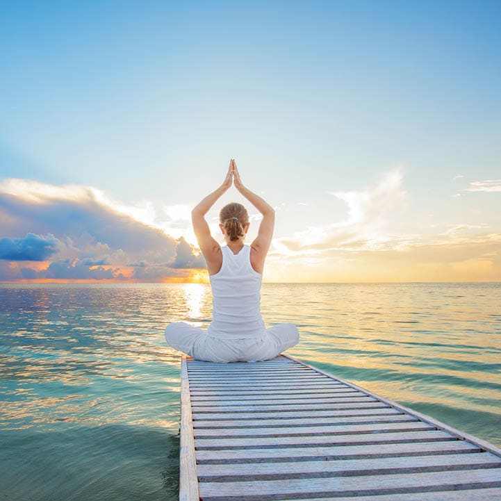 Caucasian woman practicing yoga at seashore