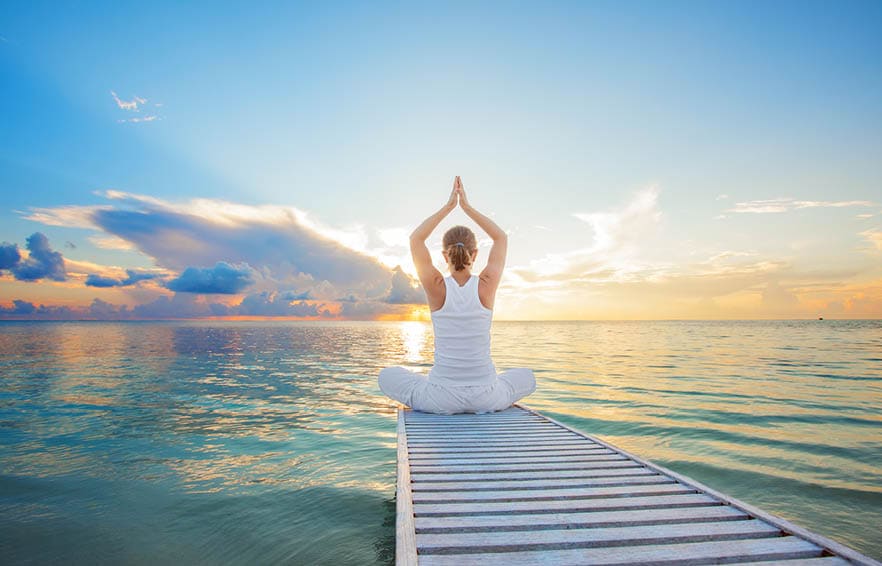 Caucasian woman practicing yoga at seashore