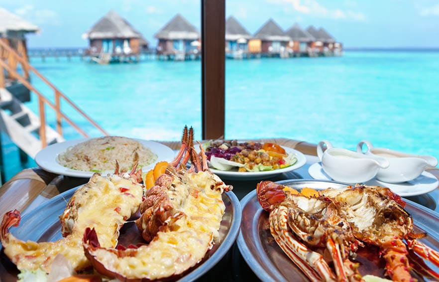 Two plates with lobster on table at window with view on ocean
