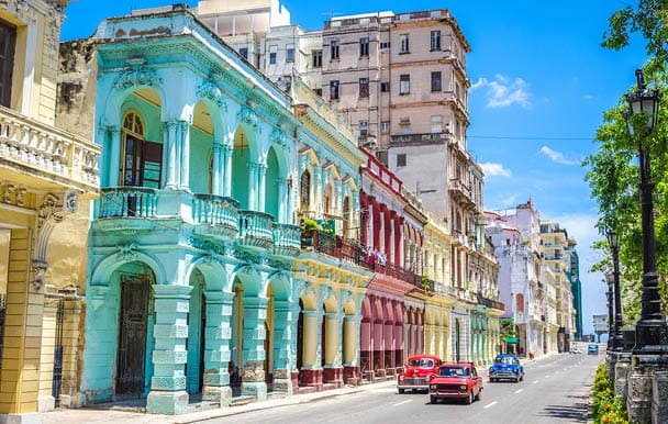 Old american classic cars on street of Havana against multicolored historic buildings
