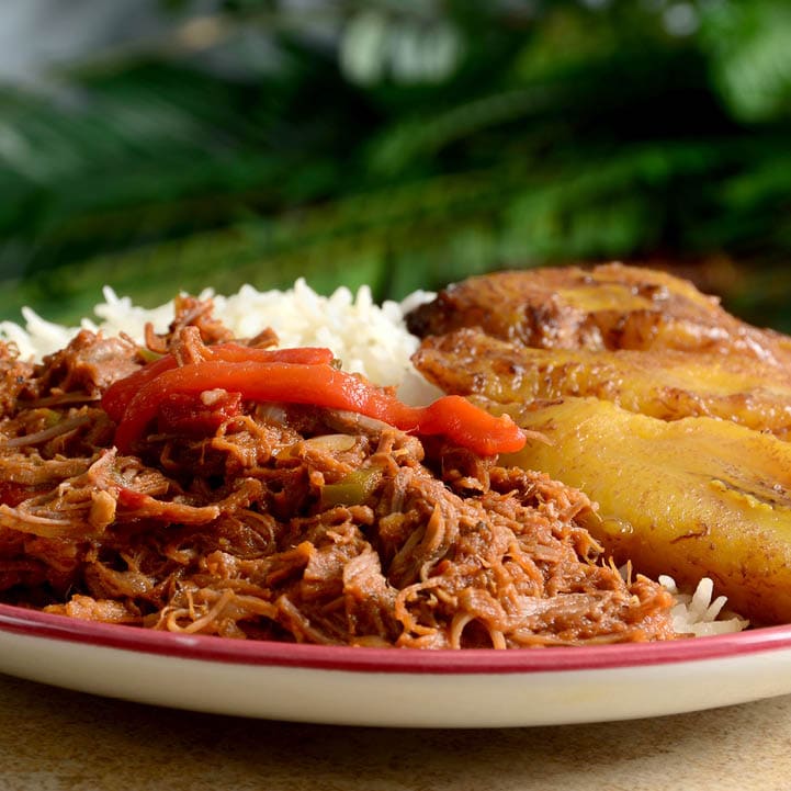 Ropa Vieja is a classic Cuban stew of shredded beef, served here with white rice and fried plantains.