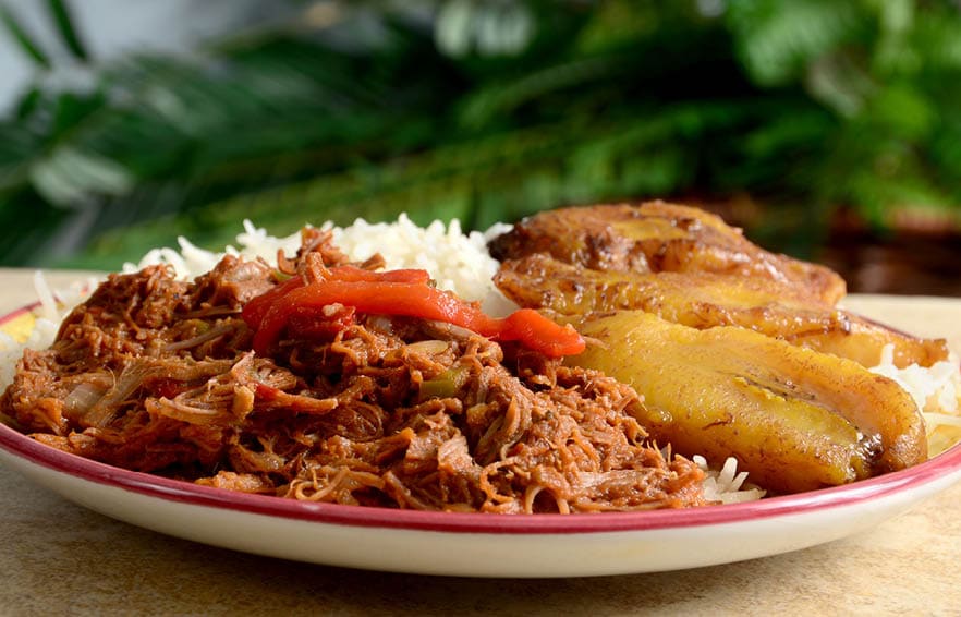 Ropa Vieja is a classic Cuban stew of shredded beef, served here with white rice and fried plantains.