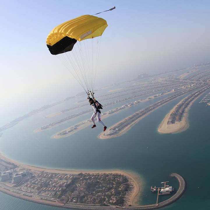 Dubai dream.Yellow extreme skydiving activity fun people on Dubai palm Jumeirah. Skydive Dubai jump travel. Yellow fun parachute jump. Summer outdoor sky activity. Big goal