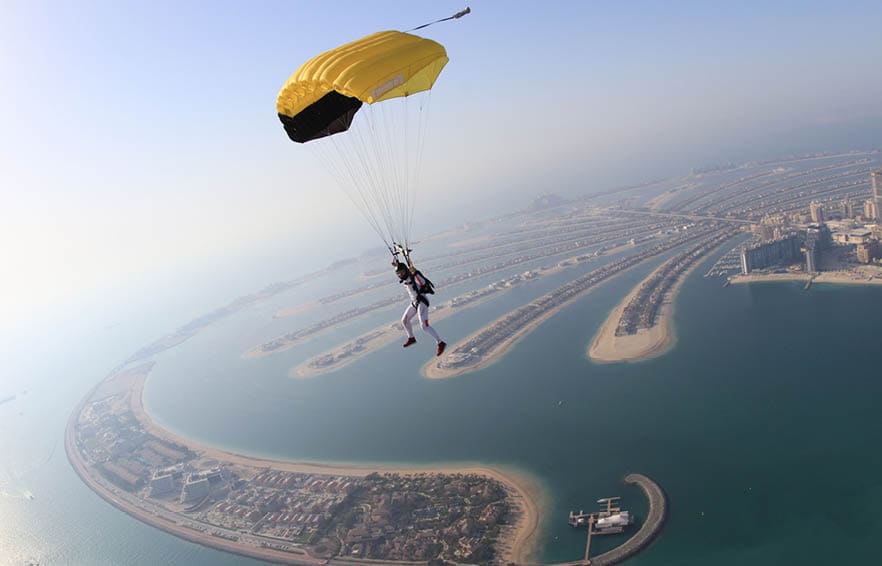 Dubai dream.Yellow extreme skydiving activity fun people on Dubai palm Jumeirah. Skydive Dubai jump travel. Yellow fun parachute jump. Summer outdoor sky activity. Big goal