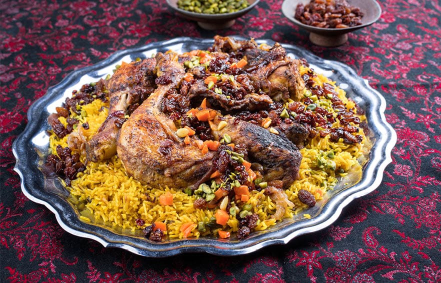 Traditional fried Arabic chicken majboos with chicken leg and jeweled rice served as close-up in a rustic oriental tray 