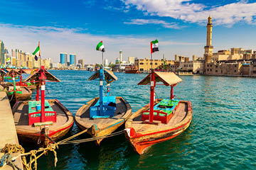 Abra - old traditional wooden boat and Grand Bur Dubai Masjid Mosque on the bay Creek in Dubai, United Arab Emirates
