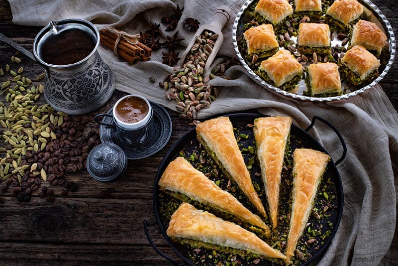 Baklava with pistachio in the plates. Carrot piece and dry baklava. Desserts with sugar syrup. 