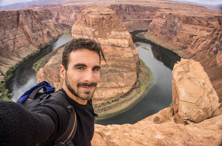 A young happy traveler taking a selfie. Horseshoe Bend on the Background. Page, Arizona