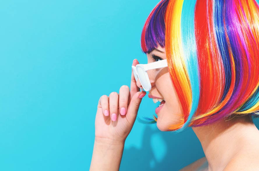 Beautiful woman in a colorful wig on a blue background