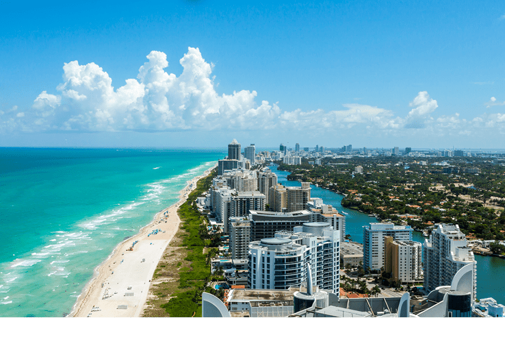 Looking down South Beach in Miami. Full view of the beach on the left and the city on the right. Beautiful blue sky on a clear day. 