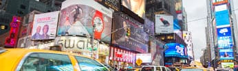 Yellow taxi cabs in traffic on 7th Avenue at Times Square, Broadway, Midtown Manhattan, New York City. Times Square is is brightly lit by neons and billboards and is part of the theater district in Manhattan. It is also one of the main tourist attractions of the city with nearly 40 million tourists visiting it yearly.