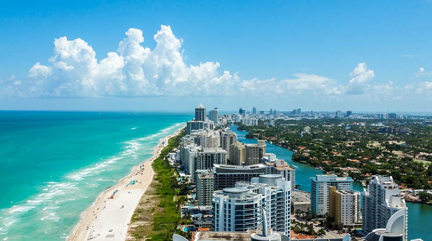Looking down South Beach in Miami. Full view of the beach on the left and the city on the right. Beautiful blue sky on a clear day. 